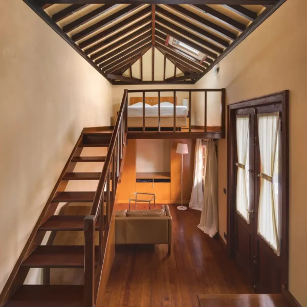 Habitación dúplex con escalera de madera, altillo y luz natural en el Hotel San Roque