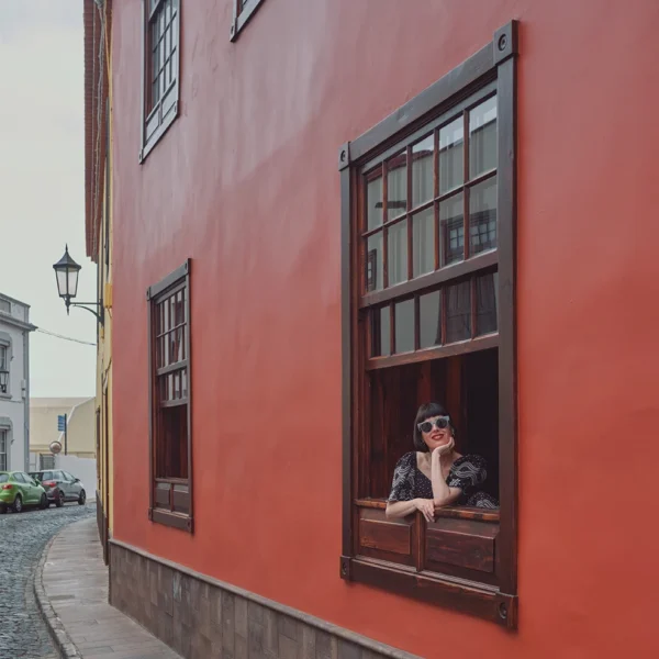 Escapadas especiales - Fachada del Hotel San Roque con huésped asomada a la ventana en una calle de Garachico
