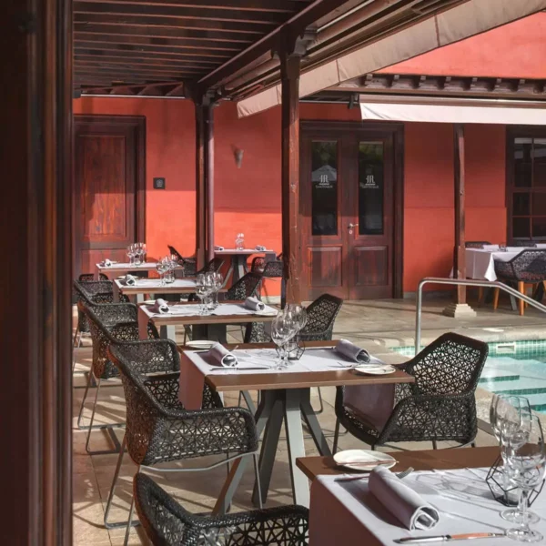 Mesas del restaurante Anturium junto a la piscina en el Hotel San Roque