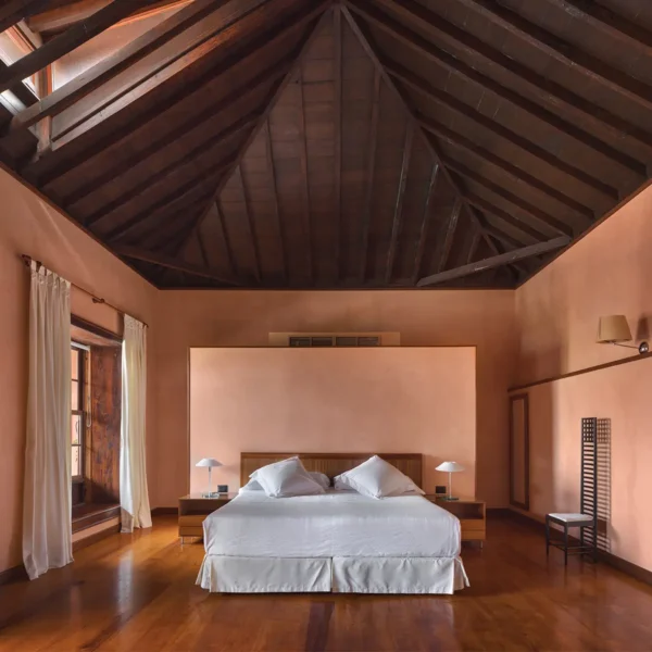 Junior suite con techo de madera, cama central y luz natural en el Hotel San Roque