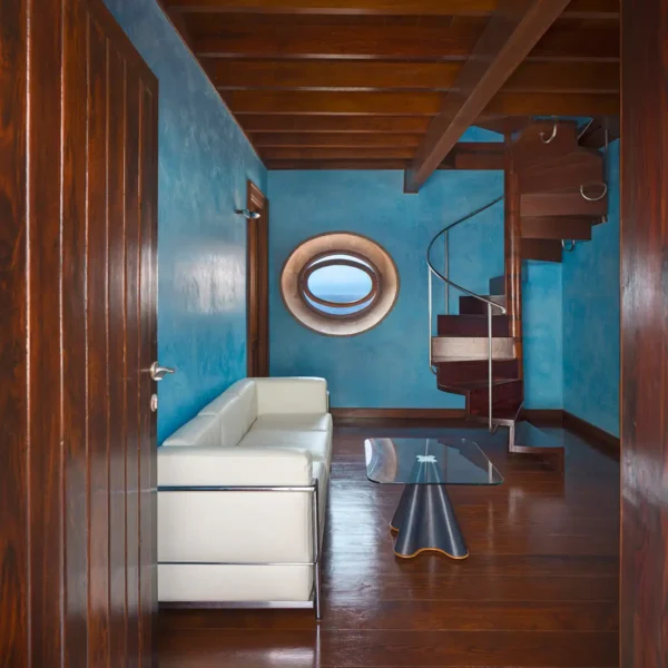 Sala de estar de la suite La Torre con ventana ovalada y escalera interior en el Hotel San Roque