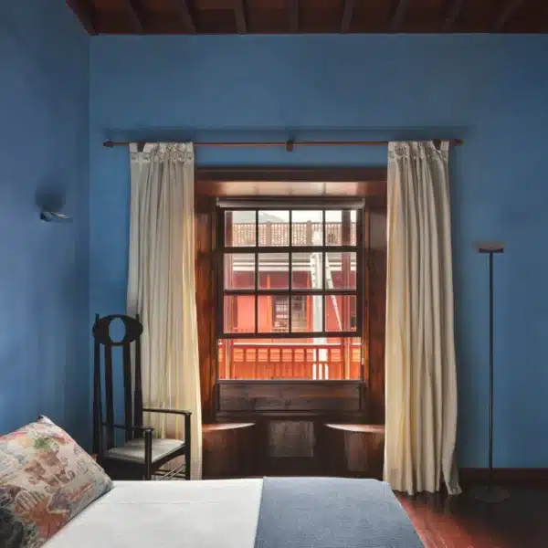 Habitación doble superior con paredes azules y vistas al patio principal del Hotel San Roque
