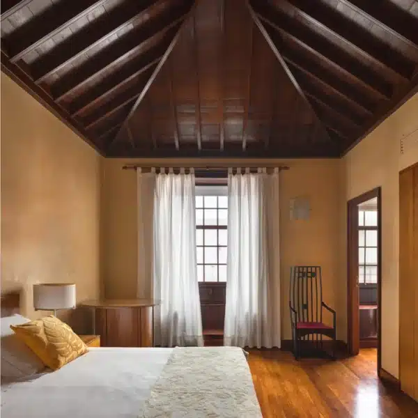 Habitación con cama, techo de madera tradicional y luz natural en el Hotel San Roque